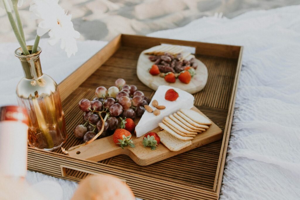 Healthy snack tray with cheese, crackers, grapes, strawberries, and nuts on a wooden serving board