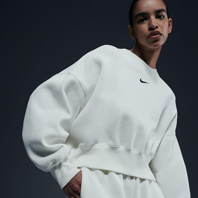 Nike Women's Phoenix Oversized Crewneck Sweatshirt – Soft Fleece, Casual & Trendy for Daily Wear A woman wearing the Nike Sportswear Phoenix Fleece oversized crewneck in Sail/Black, paired with leggings, standing in a relaxed pose that highlights the dropped shoulder seams and relaxed fit.