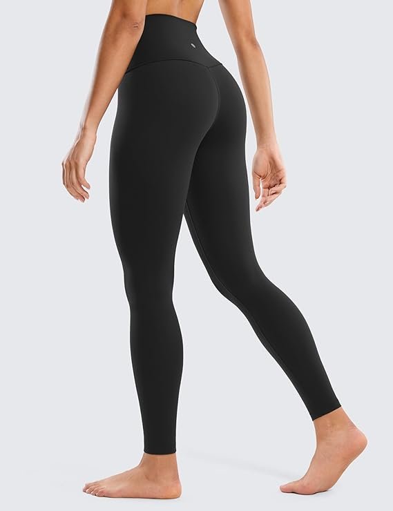 A woman wearing the black CRZ YOGA Butterluxe high-waisted leggings in a peaceful yoga pose on a mat, showcasing the buttery soft fabric and full-length 28-inch inseam.

