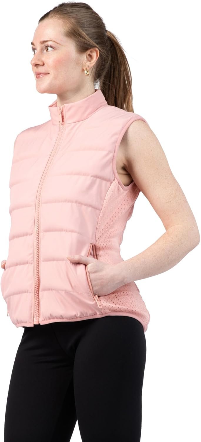 Women's Weighted Vest Review 2026: The Stylish Way to Boost Your Daily Walks A woman wearing a dusty rose, quilted, weighted vest over a casual outfit is walking outdoors on a path surrounded by greenery, smiling and looking energized.