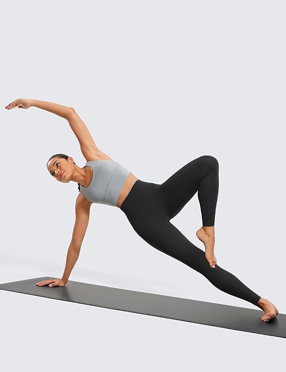 A woman wearing the black CRZ YOGA Butterluxe high-waisted leggings in a peaceful yoga pose on a mat, showcasing the buttery soft fabric and full-length 28-inch inseam.