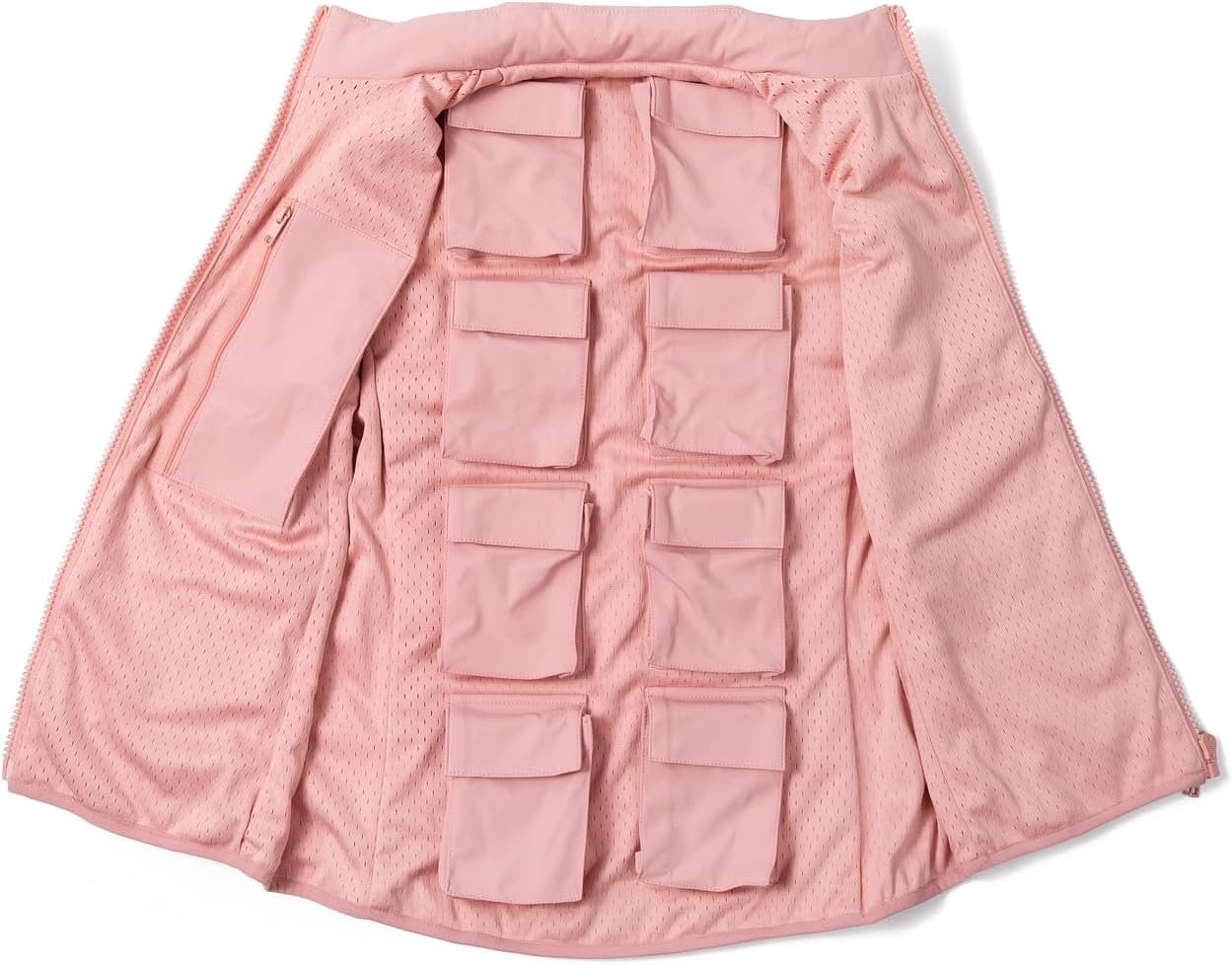 A woman wearing a dusty rose, quilted weighted vest over a casual outfit, walking outdoors on a path surrounded by greenery, smiling and looking energized.