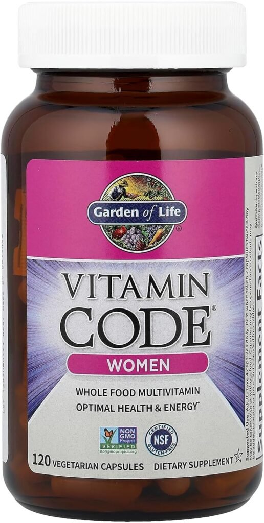 A bottle of Garden of Life Vitamin Code Women multivitamin capsules placed next to fresh organic fruits and vegetables like spinach, berries, and apples on a wooden surface.