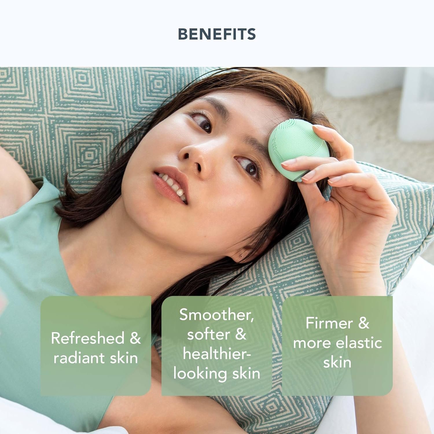 A close-up of the teal FOREO LUNA 4 Go facial cleansing and massaging device, held in a woman's hand against a soft, natural background with plants.