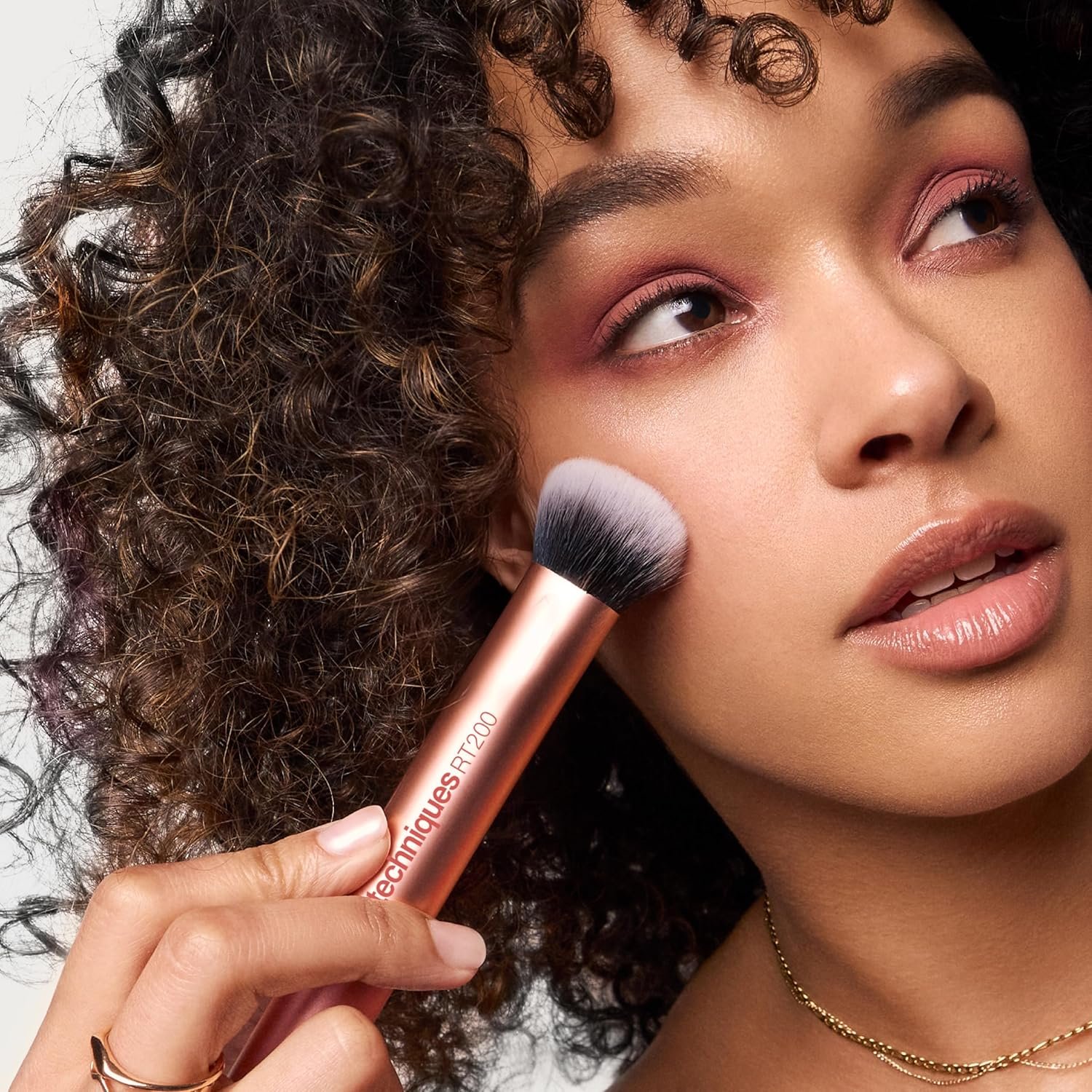 The Real Techniques A 5-piece Everyday Essentials makeup brush set laid flat, featuring four makeup brushes and one orange Miracle Complexion Sponge on a clean white background.